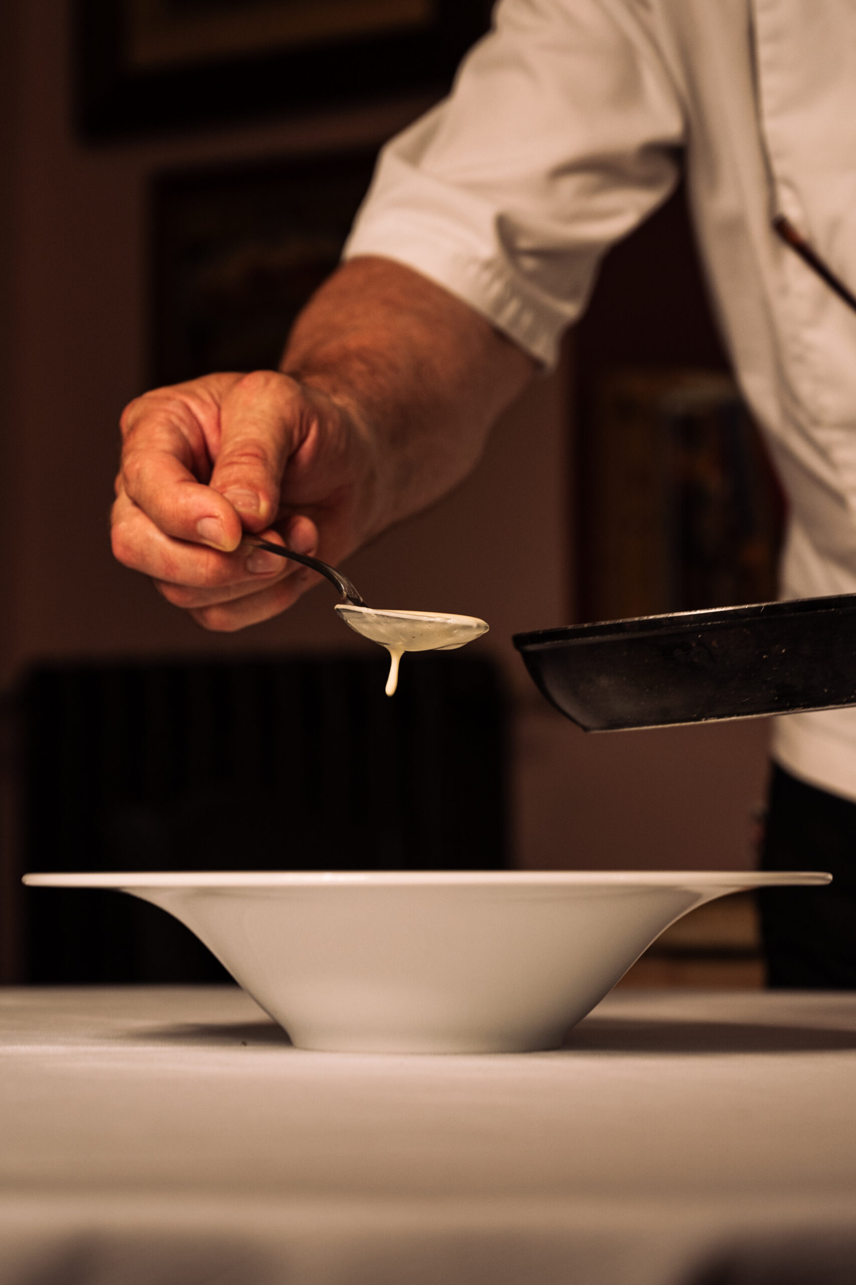 Chef versa salsa su piatto bianco